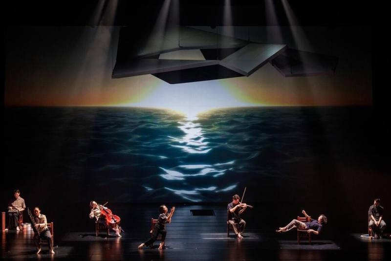 新古典室內樂團「旗津白玫瑰．25紀事」聲景紀實音樂劇場在台北國家戲劇院登場，演奏家和肢體藝術家們透過當代音樂與聲景素材等元素，重新演繹歷史。（新古典室內樂團提供）