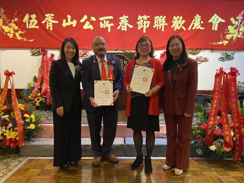 駐洛杉磯辦事處副處長陳令欣(左1)、洛杉磯文教中心主任鍾佩珍(右1)代表僑委會委員長徐佳青致頒賀狀予該公所續任主席伍永強(左2)，及新任副主席伍碧荷(右2)