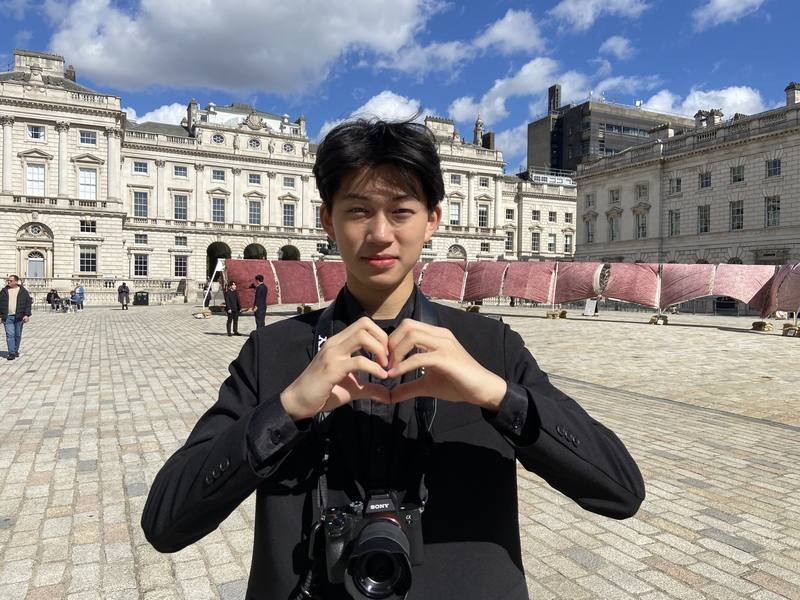 台灣青年吳典積在英國倫敦薩默塞特宮廣場比出愛心手勢，獲得年度青年攝影師獎。吳典積說，他說，他感到非常興奮，也很感激有這機會能前來倫敦領獎。