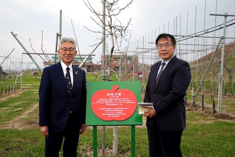 台南市長黃偉哲（右）4月前往日本青森縣弘前市參訪，與弘前市長櫻田宏（左）到當地蘋果公園，在2011年總統賴清德擔任台南市長時造訪弘前所植蘋果樹旁，種下象徵友誼的蘋果樹。（台南市政府提供）