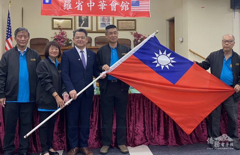 駐洛杉磯辦事處處長紀欽耀將中華民國國旗授予團長聶澤英主席(右2)、副團長張麗卿監事長(左2)、副主席朱栢田(右1)及副監事長伍堅偉(左1)