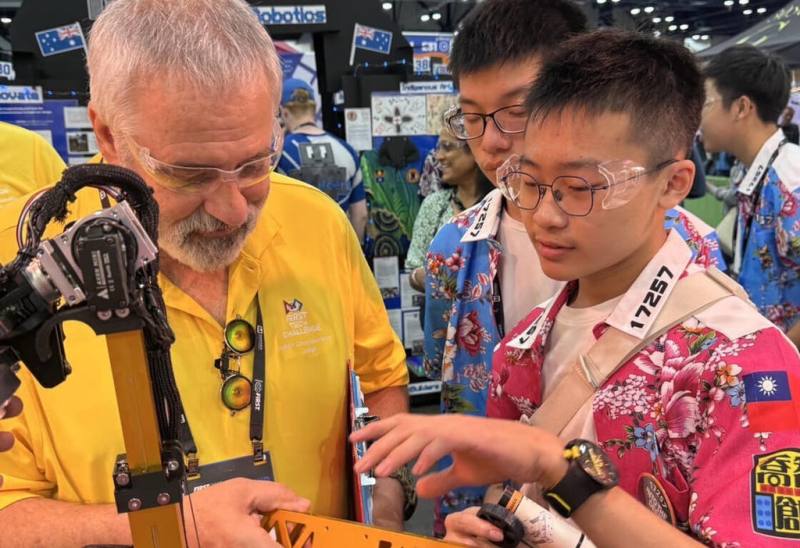 2025年FIRST世界機器人冠軍賽於美國休士頓舉行，台灣隊成員身著客家花布襯衫及醒獅帽出賽。圖為雲林正心高中代表向評審解說機器人設計。（駐休士頓辦事處提供）