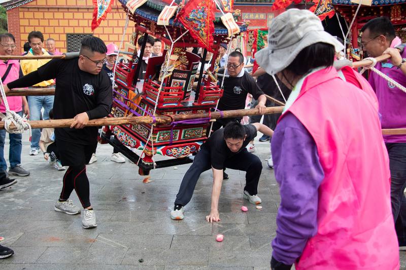 A man braves the risk of being struck by a palanquin carrying a deity statue as he scrambles to snatch a red duck egg during the Bee Worship Ritual outside Fengshang Tianhou Temple in Jinhu Township, Kinmen, on Sunday.CNA photo April 20, 2025