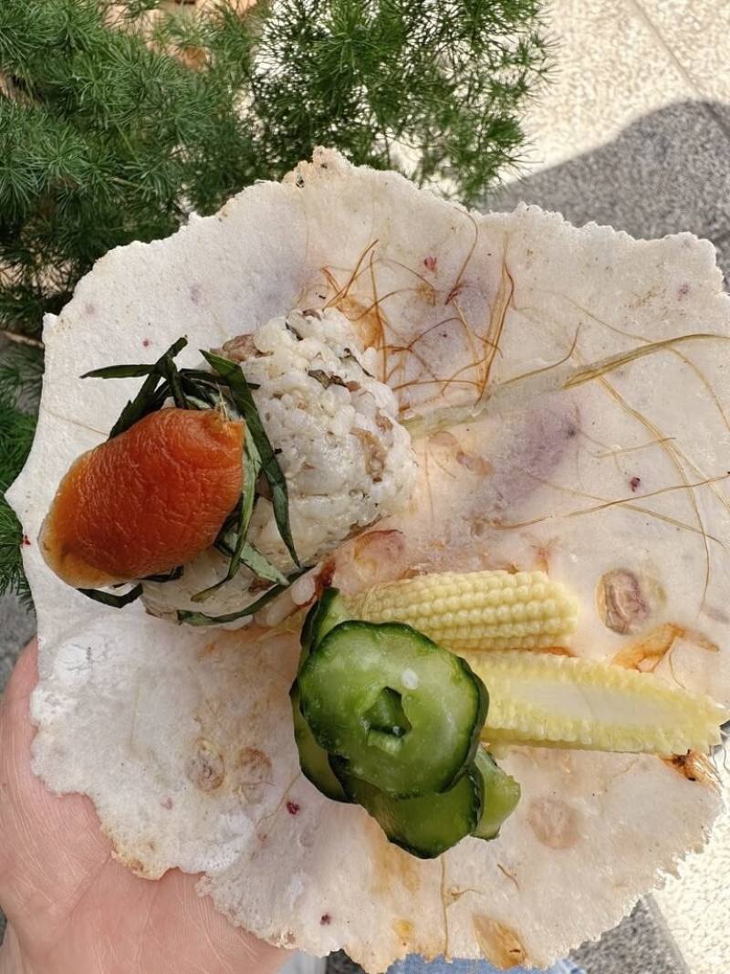 苗栗白沙屯媽祖進香在即，苗栗縣通霄鎮農會攜手綠色餐飲指南倡議「無塑進香」，設計「彩虹玉米仙貝飯糰」作為創新示範綠色飯擔，盛裝器皿採用在地越光米和彩虹玉米研磨、低溫烘焙製成，完全可食。（綠色餐飲指南提供）