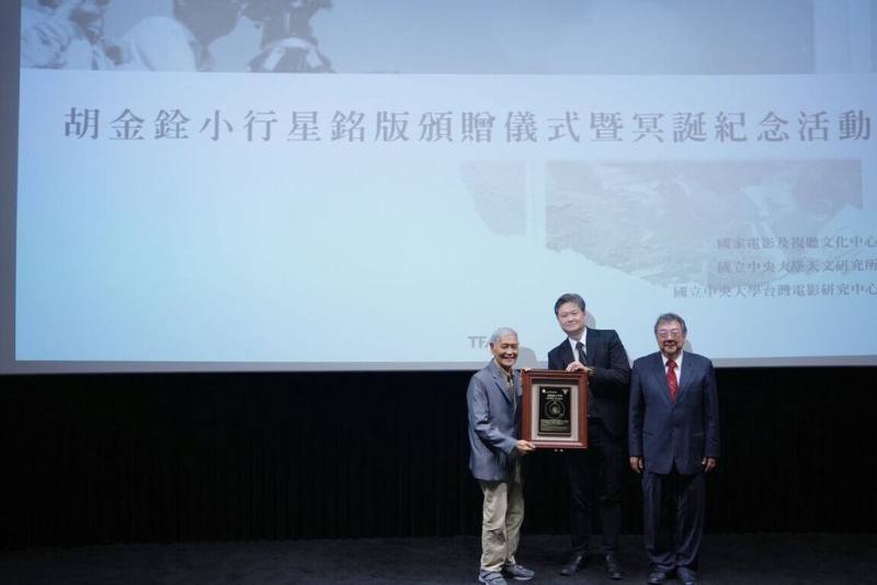 為緬懷已故武俠電影導演胡金銓，中央大學將編號600867號小行星命名為「胡金銓（Kinghu）」，並由資深演員石雋（左）代表受贈小行星銘版。（中央大學提供）