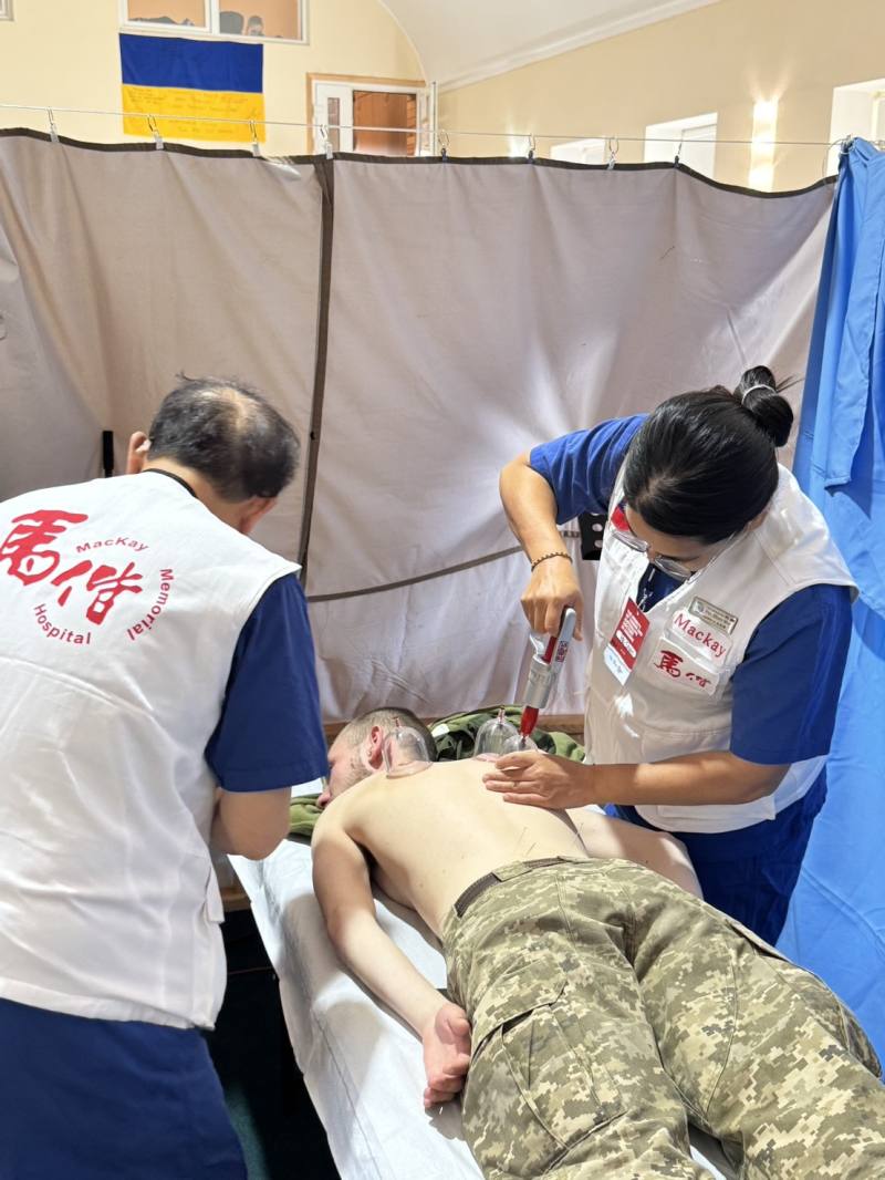 馬偕中醫部主任陳光偉及急診醫學科醫師吳佩珊於烏克蘭茲維亞赫爾(Zviahel)教堂為軍人做傳統醫學治療。(馬偕醫院提供)