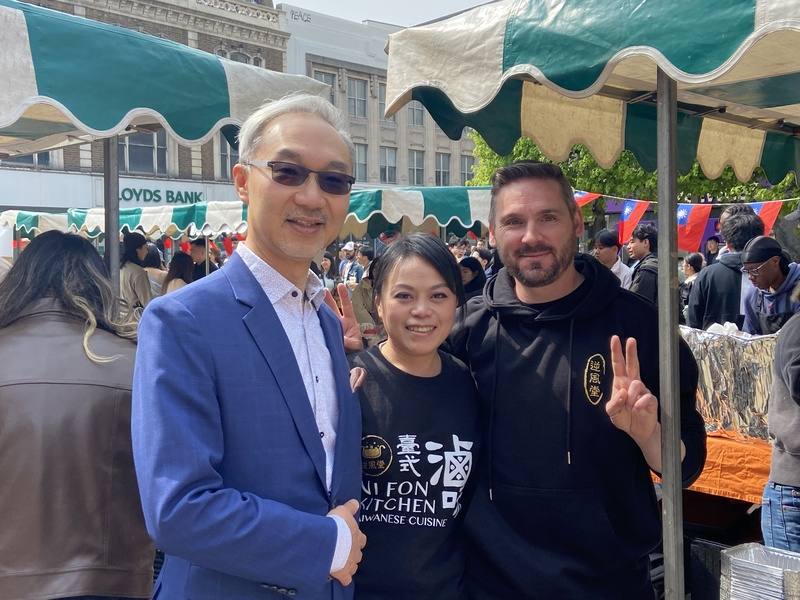 旅居英國的台灣人劉佳昕（中）和來自羅馬尼亞的男朋友一起賣台式滷味。駐英國代表姚金祥（左）參觀她的攤位後，一起合影