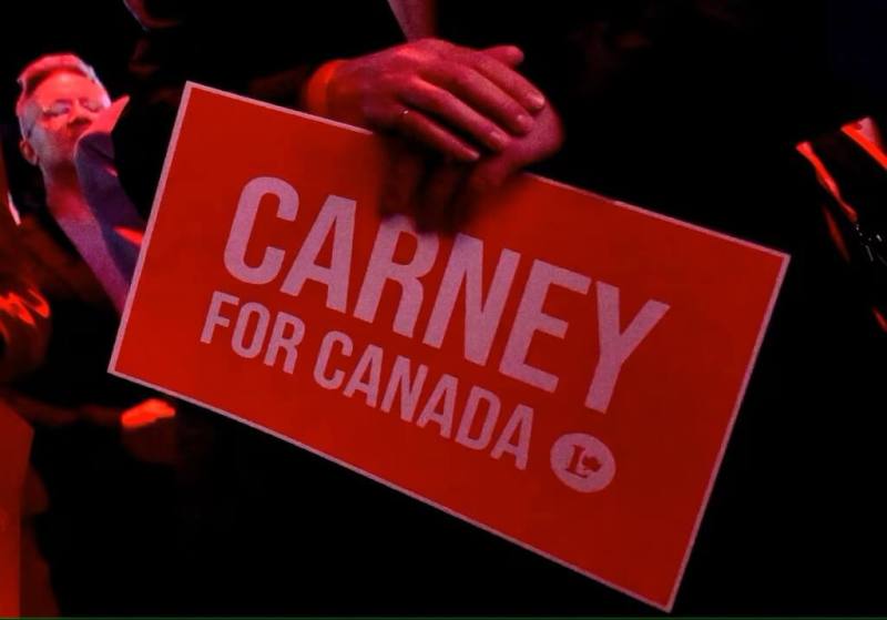 加拿大自由黨競選總部民眾手拿支持總理卡尼標語。（路透社）