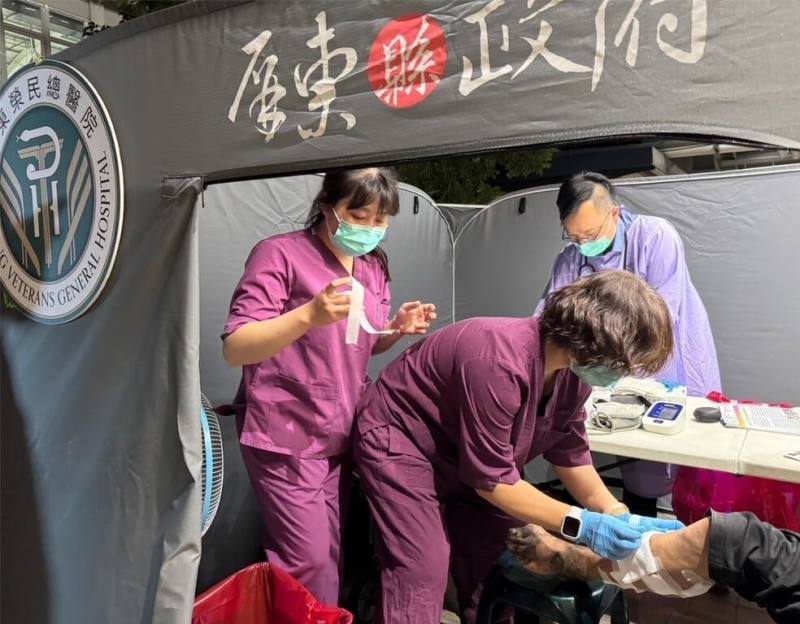 屏東縣政府結合屏東榮民總醫院等團體，為街友提供醫療外展服務，首場看診29日晚間在屏東火車站登場，護理師為看診民眾包紮。（屏東縣政府社會處提供）