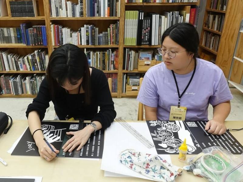 教育部2日發布新聞稿，介紹「青年暑期社區職場體驗計畫」。參與計畫的曹孟涵（左起）、陳欣庭前往台灣非視覺美學教育協會，協助製作展覽會的作品講解海報、點字及語音導覽QR Code。（教育部提供）