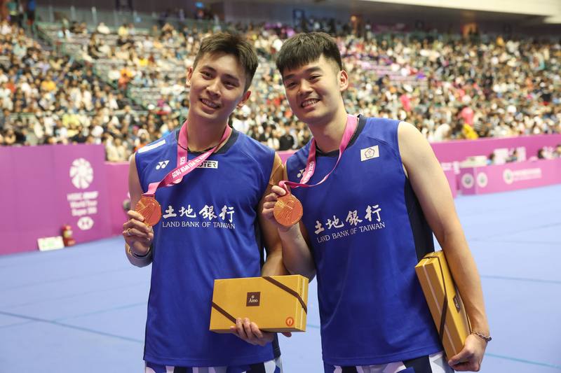 Taiwanese Olympic badminton men's doubles gold medalist Wang Chi-lin (right) and his new partner Chiu Hsiang-chieh (left) showcase their men's doubles title won at the Taipei Open on Sunday, becoming the first local women's team to win the tournament in 1