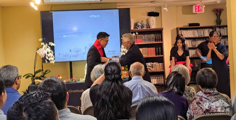 慈濟邁阿密聯絡處林明哲師兄(右)致贈國旗領巾予周啟宇(左)