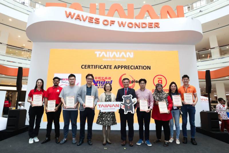 台灣旅展16日在馬來西亞檳城開幕，觀光署駐吉隆坡辦事處主任周士弼（右5）與參展人員合影，盼推動體驗台灣多元文化魅力。（觀光署駐吉隆坡辦事處提供）
