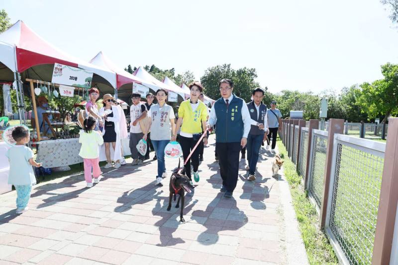 「野餐我PET你．滾草皮音樂市集」由日本眼鏡品牌JINS主辦，18日在台南市安平寵物運動公園登場，市長黃偉哲（前右）也帶著愛犬「黑妞」現身參與。（台南市政府提供）