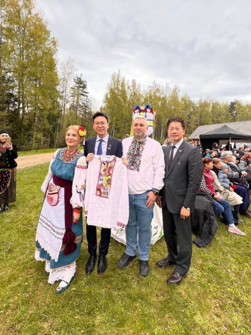 國安會副秘書長林飛帆（左2）18日應「烏克蘭人在愛沙尼亞組織協會」之邀，出席「刺繡衫節-維希凡卡團結」嘉年華活動，協會主席帕拉瑪（右2）致贈傳統刺繡衫上衣。（駐拉脫維亞代表處提供）