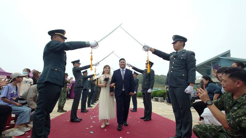 連江縣政府民政社會處20日於南竿北海坑道前舉辦首屆聯合婚禮，馬祖防衛指揮部官兵身著正式軍裝，手舉長劍組成8道「劍門」，具有「雙劍合璧」寓意，參加新人依序穿越