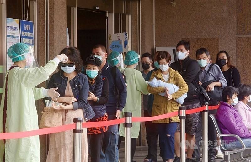 Patients wait in line to get their temperatures taken before entering a hospital in this CNA file photo