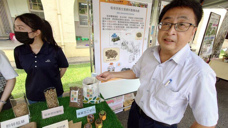 農業部農業試驗所農業化學組副研究員張明暉（右）24日在嘉義農業試驗分所解說如何回收稻草再利用，農試所研發固態生質燃料製作技術，配合輸送帶建構製造生產系統，將稻草製成固態生質燃料。