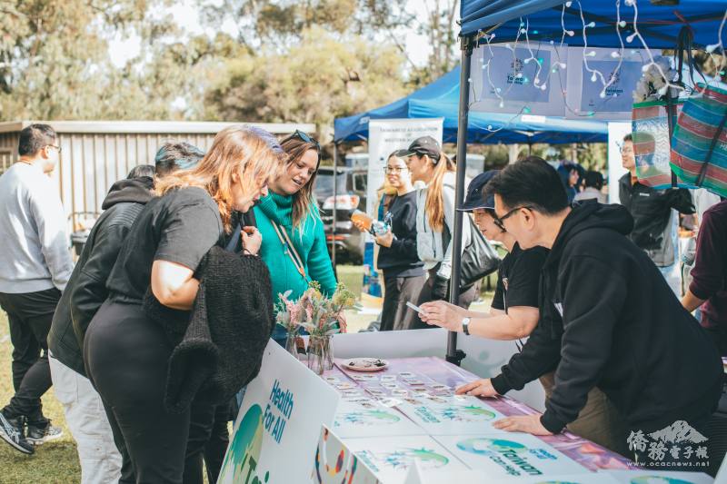 西澳僑務委員張嘉甫與西澳台灣客家會會長張晏華向民眾介紹僑委會小禮物