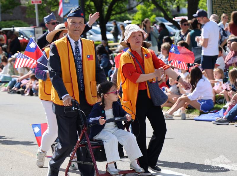 海軍退役軍官暨密西根榮光會創會會長鄭東南，身著軍帽、神情堅毅，於國殤日大遊行中與夫人及孫女同行，象徵榮民對國家的忠誠與對世代傳承愛國的精神