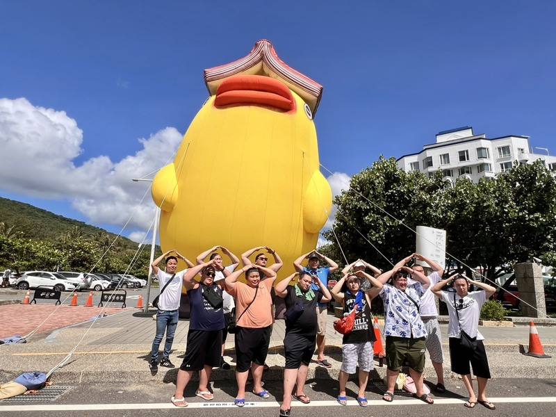 Sumo Master Shikoroyama Tsuneyuki and wrestlers visiting from Japan pose for a group photo in front of Taiwanese artist A-Lei's (阿咧) "Book Duck" created as a giant inflated installation for the "There's Monsters" exhibition at Luo Shan Feng Recreation Are