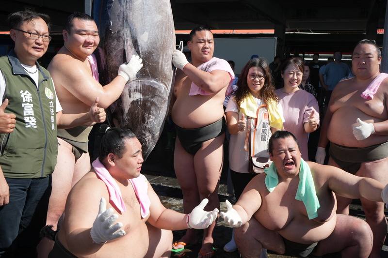 Legislator Hsu Fu-kuei (徐富癸, left) and visiting sumo wrestlers pose for the press with a bluefin tuna at Donggang Fishery Port in Pingtung County Monday. CNA photo June 9, 2025