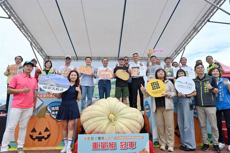 Farmer Lin Chien-hsun (seventh left in back) poses with New Taipei Mayor Hou Yu-ih (sixth left in back) behind the former's award-winning heavy pumpkin. Others at the event include other competitors and also New Taipei agricultural officials. Photo courte