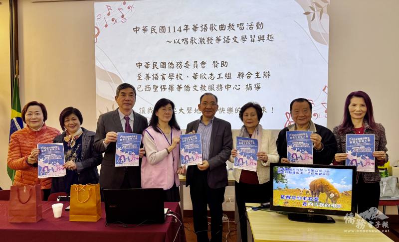 貴賓持2025全球僑校學生暨僑生歌唱大賽海報合照，右起為巴西華人資訊網創辦人支黃秀莉、僑務諮詢委員洪慈和、僑務委員洪呂麗月、聖保羅文教中心主任尤正才、校長趙士縈、僑務諮詢委員張宏昌、聖保羅國際傑人會副會長林玉琴、顧問涂宋如平