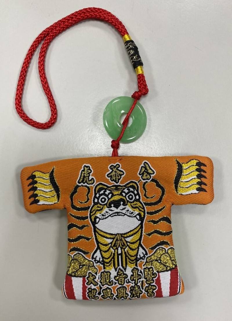 台南市北區興濟宮和台南市警局第五分局聯手打造限量聯名「虎力五保庇」小神衣吊飾，正面以虎紋為底，衣袖處五爪造型象徵虎虎生風、趨吉避凶，預定6月30日虎爺聖誕（農曆6月6日）亮相。（興濟宮提供）