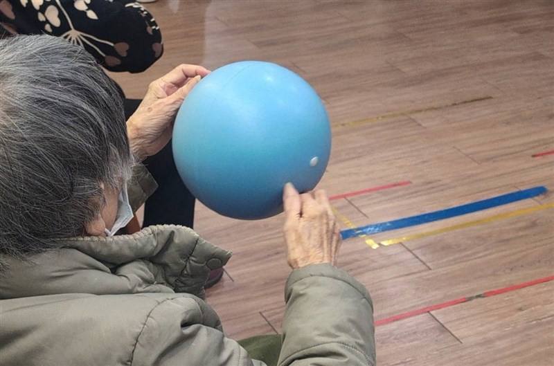 An individual suffering from dementia practices holding a ball with both hands. CNA file photo