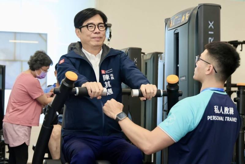 高雄市岡山運動中心21日開幕，高雄市長陳其邁（中）參觀場館與泳池，並在教練指導下體驗健身設備。（高雄市政府提供）