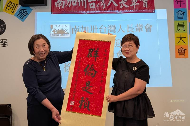 徐佳青（右）贈致「群僑是賴」書法掛軸予南加州臺灣人長輩，由會長江美娟（左）代表接受