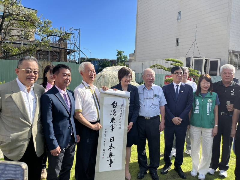Akie Abe (fourth from left) poses with a piece of calligraphy given to her by a member of the public, alongside various officials including Kaohsiung Mayor Chen Chi-mai (third from right), during a temple visit on Saturday. CNA photo June 21, 2025