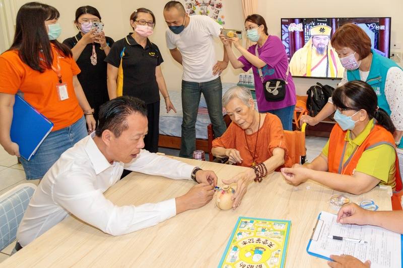 嘉義縣長翁章梁（前左1）23日化身「類家屬」，前往老人長期照顧中心擔任「一日關懷人」，與專業關懷人員陪伴無家屬照護長者楊奶奶，傳遞溫暖與關懷。