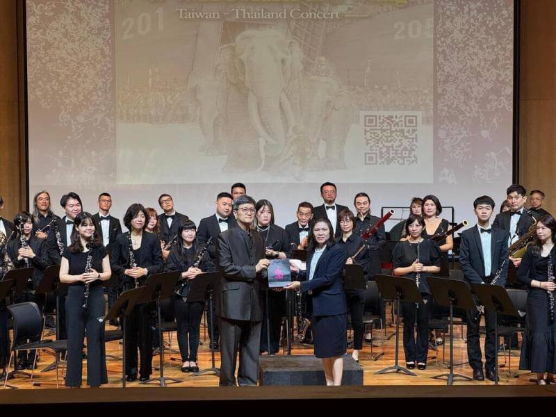 台北市民管樂團、樂團指揮何康國（前左）及金鼎獎作家李如青合作，以繪本作品「大兵林旺三部曲」為靈感舉辦台泰交流音樂會。圖為6月20日在泰國藝術大學舉行的音樂會。（駐泰代表處提供）