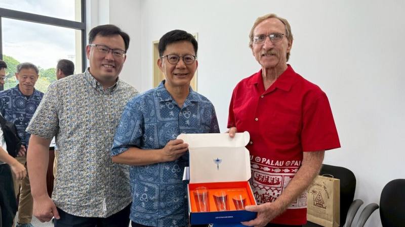 教育部次長張廖萬堅（中）及體育署長鄭世忠（左）受邀赴帛琉參加「第12屆太平洋迷你運動會」，29日與教育顧問詹金斯（Dale Jenkins）交換禮物。（體育署提供）