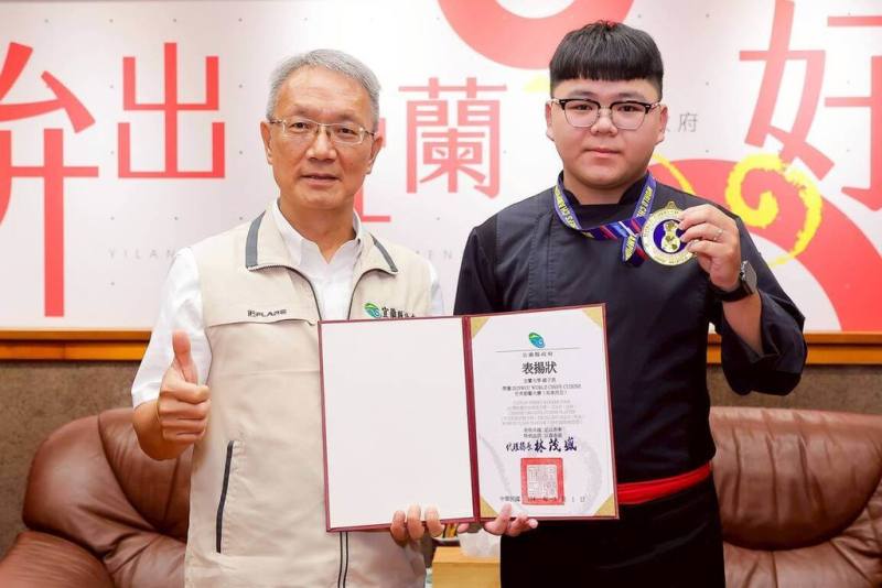 就讀國立宜蘭大學的羅子恩（右）將宜蘭名菜西魯肉融入菜餚，榮獲「世界廚藝大賽」2面金牌與廚師獎，宜蘭縣代理縣長林茂盛（左）1日接見羅子恩及參賽團隊。（宜蘭縣政府提供）