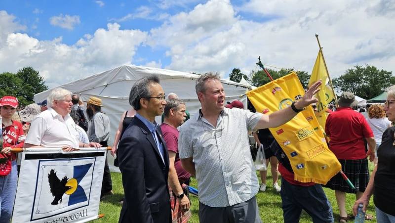 加拿大傳教士馬偕故鄉安大略省牛津郡舉辦恩布羅高地運動會，駐多倫多辦事處長梁毅鵬（前左）與上百位台僑應邀參與盛會，牛津郡長萊恩（前右）介紹運動會。（駐多倫多台北辦事處提供）