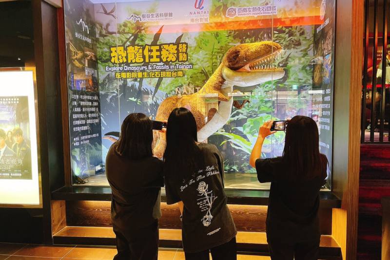 台南樹谷生活科學館與左鎮化石園區暑期推出「恐龍任務」系列活動，左鎮化石園區巨型暴龍玩偶現身南台影城大廳，吸引民眾拍照。（台南市文化局提供）