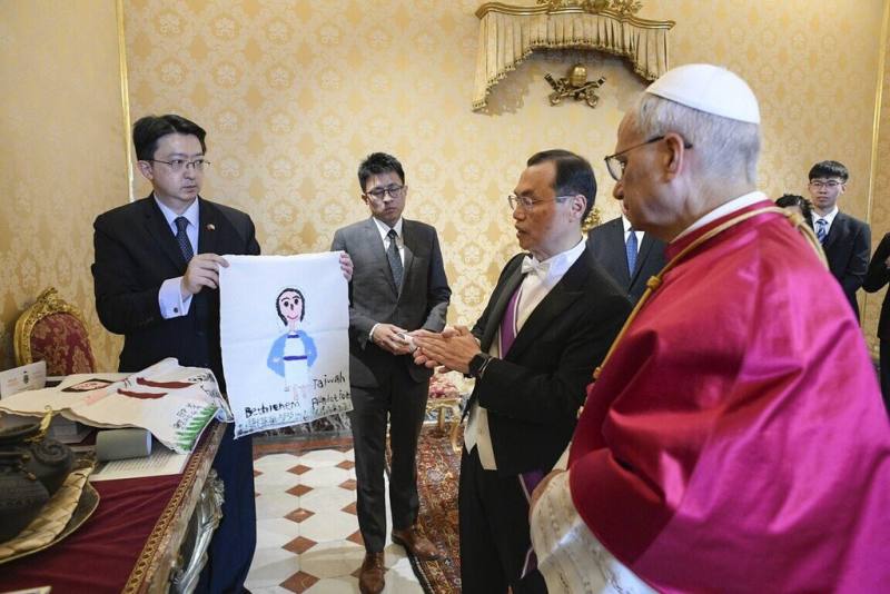 駐教廷大使賀忠義（右2）3日向教宗良十四世（白帽者）致贈台灣兒童畫作，這是總統賴清德在台南市長任內支持的台南「伯利恆早療中心」孩童手繪的聖母、耶穌等畫像。（駐教廷大使館提供）