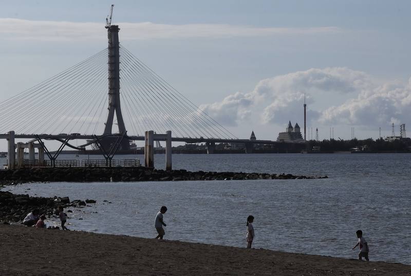 颱風丹娜絲逐漸逼近，中央氣象署表示，6日各地都會下陣雨或雷雨，需留意颱風東半側強風範圍很廣。圖為午後在八里渡船頭一帶，有孩童在沙灘上玩耍