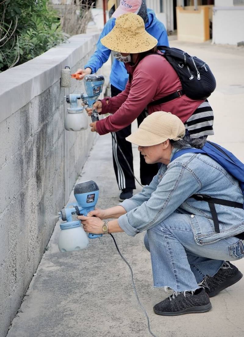 DIY工作坊學員運用成大昶閎研發的在地材料「樂土細蚵灰」，以噴塗、滾塗技法為澎湖紅羅社區改造牆面。（成大昶閎提供）
