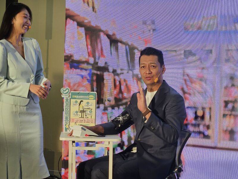 衛生福利部國民健康署與台灣高血壓學會22日舉行記者會，呼籲18歲以上民眾1年1次「722在家量血壓」，藝人聶雲（右）以短劇呈現定期且正確量血壓的重要性，並引出安心血壓站的便利性