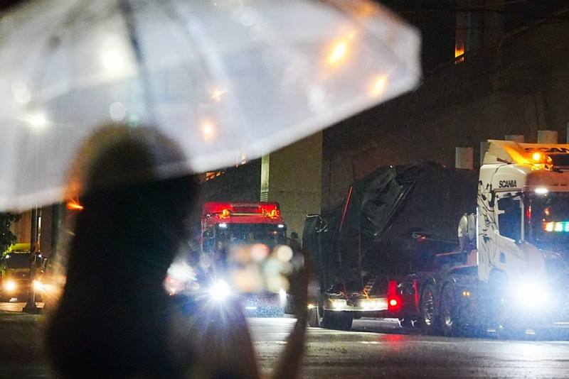 第2批M1A2T戰車27日晚間運抵台北港，裝載的卡車於28日凌晨離開港區大門。圖為民眾撐起雨傘在路口捕捉歷史性一刻。