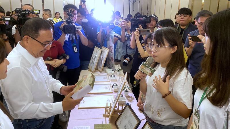 第12屆新北庇護禮發表記者會29日舉行，新北市長侯友宜（前左）出席並聽取醒吾科技大學團隊成員介紹茶餅禮盒的外包裝設計理念。