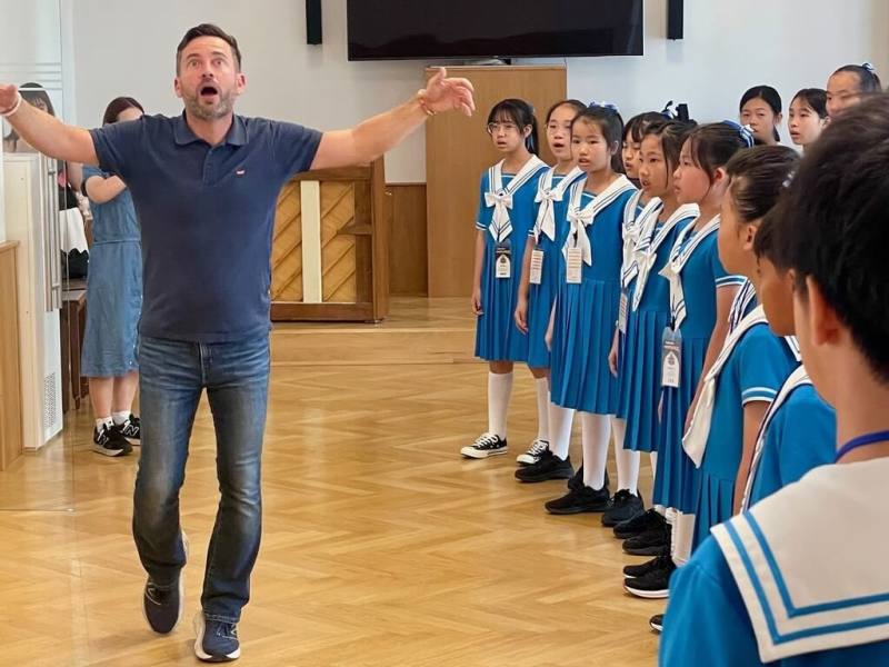 維也納少年合唱團舉行夏季合唱音樂營，藝術總監鮑姆加特納（Erasmus Baumgartner）（左）親自指導東海大學附屬高中小學部合唱團團員做發聲練習，透過活潑的互動，引導學生體會音樂的本質。（長榮駐奧地利分公司提供）