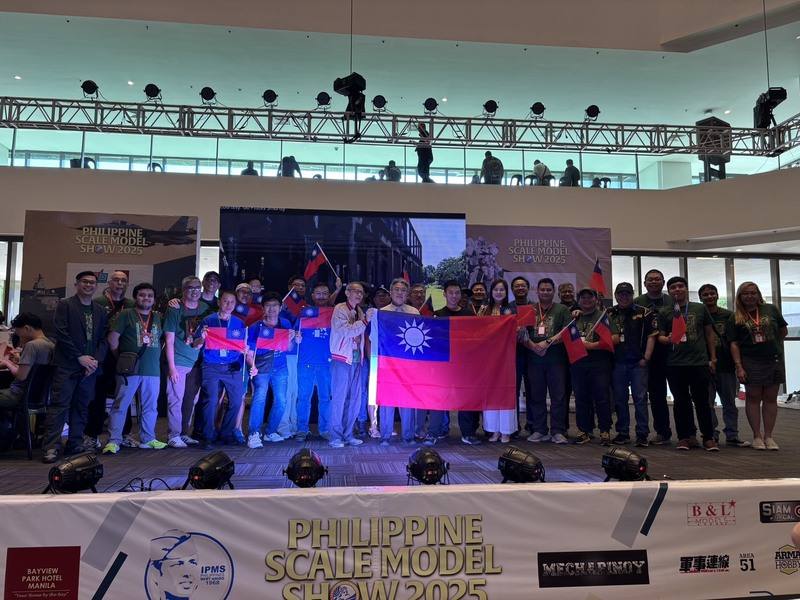 第2屆菲律賓比例模型大賽3日閉幕，台灣團隊在近800件國際模型愛好者的作品之中，勇奪4金3銀1銅，成績耀眼。圖為駐菲副代表楊登仕（前中著白衣者）與台灣團隊上台秀國旗，和主辦單位人員合影。