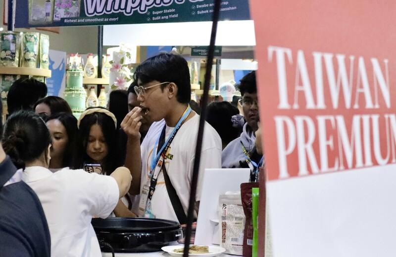 為期4天的2025年菲律賓國際食品展（WOFEX）6日在馬尼拉登場，圖為菲律賓民眾在台灣館前試吃。