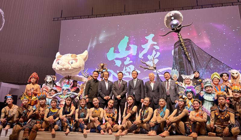 大阪世博TECH WORLD館8日於EXPO HALL舉辦「展館日」，邀請國際知名表演團隊「舞鈴劇場」演出「山海天光」，玉山數位科技株式會社榮譽會長黃志芳（站立左3）、導演劉樂群（站立左1）、大阪世界博覽會事務總長石毛博行（站立左2）、大阪府副知事山口信彥（站立右2）、TECH WORLD館長邱揮立（站立右1），於演出後合影