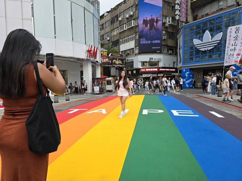 A woman poses with the renewed land art, “Rainbow Six”, in Ximending, Taipei, on Saturday. CNA photo Aug. 9, 2025